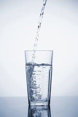 Clear mineral water is poured into a glass with ice.