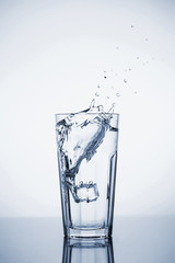 Clear mineral water splashes in a glass with ice.