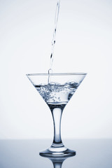 Clear mineral water is poured into a glass with ice.