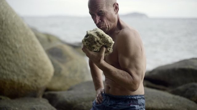 man work out, with a big stone, on the seashore