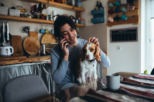young man with his dog in kitchen at home, morning scene - Powered by Adobe
