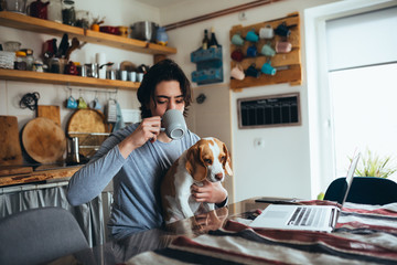 young man with his dog in kitchen at home, morning scene,