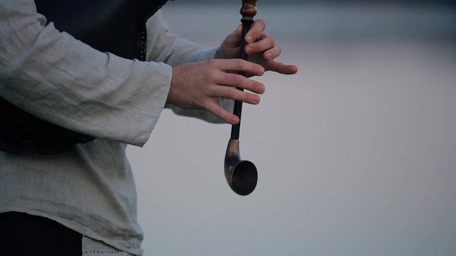 Hands of a musician on a wind flute, a man plays a melody in nature.