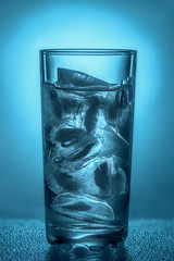 glass cup with clear water and ice cubes on a dark blue background