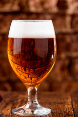 Beautiful glass of tulip light beer with foam Isolated on a beautiful brick background close-up