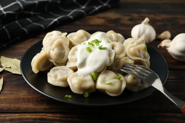 Plate with dumplings and towel on wooden background, close up