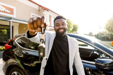 Portrait of African man car seller holding car keys. Attractive cheerful young African man smiling...
