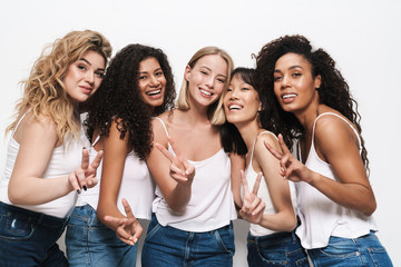 Image of pretty multinational women smiling and gesturing peace sign