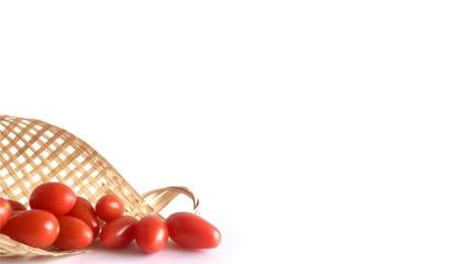 White background with small red cheery tomatoes in a bamboo basket on the bottom of the frame.