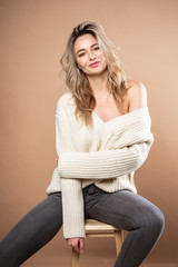 Beautiful blonde woman in a knitted sweater over brown background. Casual style, fashion beauty portrait