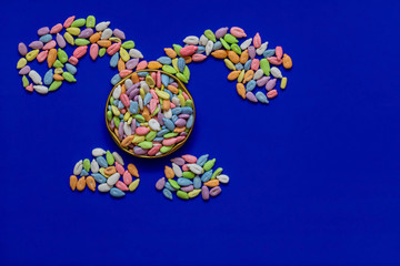 Sunflower seeds in colored glaze on a blue background laid out in the form of a rabbit. Easter, flat lay, copy space, top view.