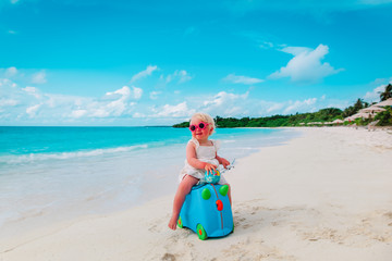 happy cute little girl with luggage and toy plane travel on beach