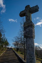 Stone cross against blue sky with clouds.