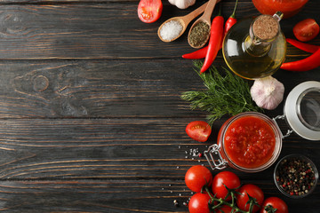 Chilli sauce, garlic, cherry tomatoes, olive oil, spices on wooden background, space for text. Top view