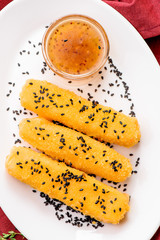 Classic beer snack. Beautiful cheese sticks decorated with black sesame seeds served with sauce