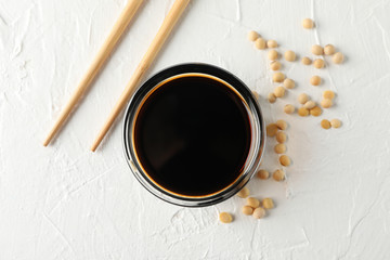 Bowl of soy sauce, soy beans on white background, space for text. Top view