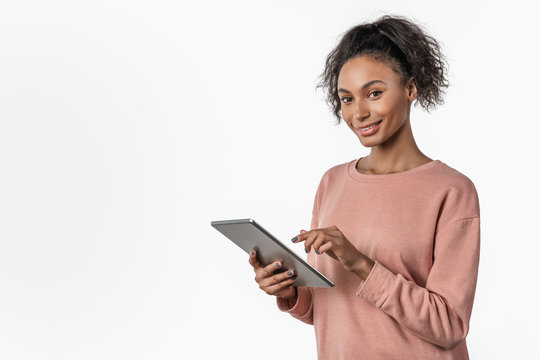 Young african woman standing and using tablet computer isolated over white background