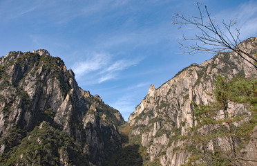 Fototapeta premium Huangshan Mountain in Anhui Province, China. View of mountain peaks, cliffs and trees at the lower part of West Sea or Xi Hai canyon on Huangshan. From the West Sea path on Huangshan Mountain, China.