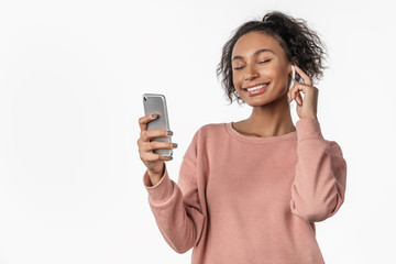 Young woman enjoying music in earphones and dancing isolated on white background