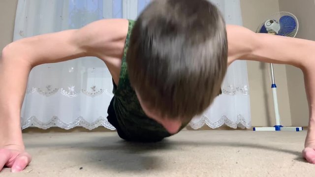 Young skinny thin Man Doing Push Ups. Teenager boy in military form shirt Making Pushups in the room at home. close up cadet training concept.