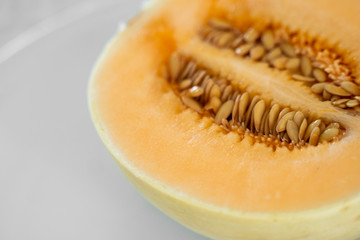 Fresh sweet orange melon on the white plate as a background with a selective focusing. Useful and vitamin-rich food. Vegeterian.