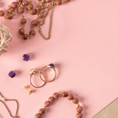 Aventurine stone bracelets, gold chains and jewelry on a pink background, top view, flat lay, copy space.