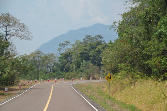 View of curve road and warning sign. Road to Bokor Mountain in Preah Monivong National Park. Cambodia, Kampot Province