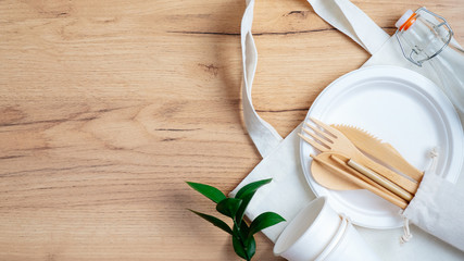 Eco natural paper cups and plate, cotton reusable produce bag, bamboo cutlery set and green leaf on...