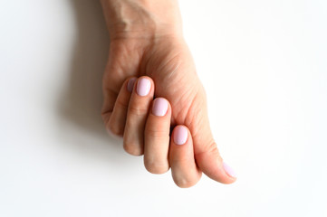 woman's hand with pale lilac painted nails on a white background
