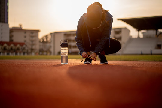 Beautiful female athletes tie shoelaces on sneakers. Beautiful female athletes are sitting on a shoelace on a black sneakers. Healthy lifestyle concepts