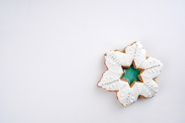 Snowflake shape gingerbread cookie on white background. Cooking, recipe, card, Christmas concept. Top view, flat lay, copy space