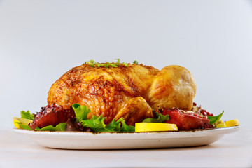 Whole roasted chicken on plate with salad and pomegranate.