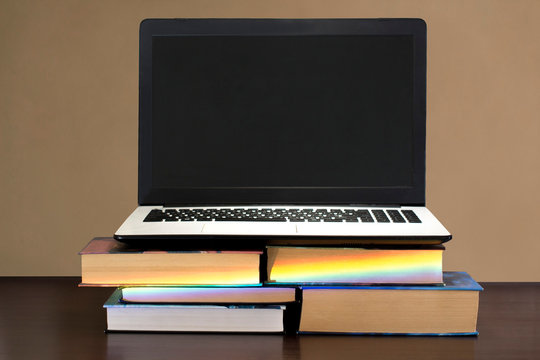 White And Black Laptop On Stack Of Books On A Dark Wooden Table