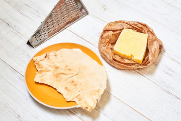 Pita and hard cheese on a light wooden background. Preparing for the preparation of snacks.