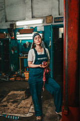 Gender equality. Portrait of a young strong woman in uniform working in a workshop, which wipes his...