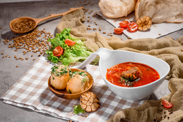 Red borsch of beets, vegetables and meat in white plate and donuts with garlic on concrete background decorated fresh vegetables and checkered napkin. Homemade Russian, Ukrainian national soup. 