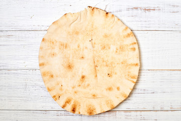 round pita bread on a light wooden background.
