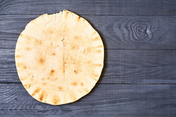 round pita bread on a dark wooden background.