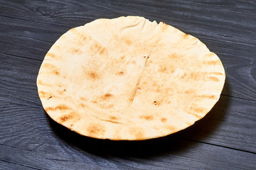 round pita bread on a dark wooden background.