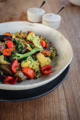 Oven baked vegetables - broccoli, pumpkin, cauliflower and zuccini - in bowl on wooden background closeup