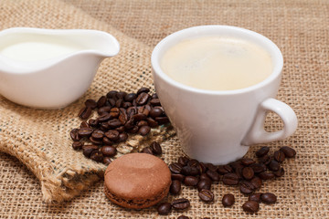 Coffee cappuccino, cream and coffee beans on sackcloth background