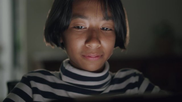Medium Close-up of Asian girl watching video via online media On tablet for entertainment And smiling happily in the home at night