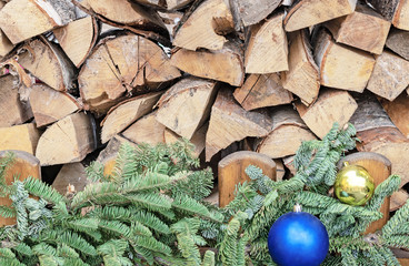 Firewood and christmas tree with toys near a wooden fence.