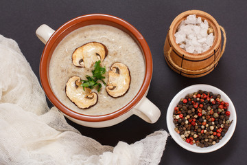 Cream soup with mushrooms in porcelain bowl on black background.