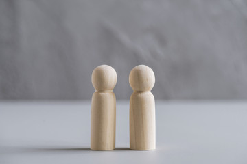 Wooden people two man against the background of a gray concrete wall. The concept of family, friendship, relationships.