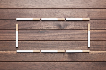 Frame of cigarettes on wooden background. Top view with copy space, flat lay