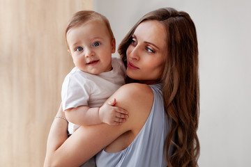 Happy childhood. Attractive Mother loves her adorable son, and small child looking at the camera with his blue eyes. Close-up portrait