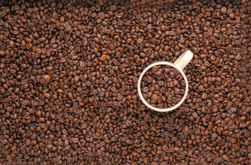 white cup of coffee with coffee grain on grain background. coffee beans top view. Coffee cup and beans view from above. Coffee close-up brown beans texture background. Overflowing beans.