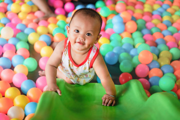 Fototapeta na wymiar Nine month old boy Playing happily with a multicolored ball, Cute Asian Boy, Happy children playing and having fun at kindergarten with colorful balls.