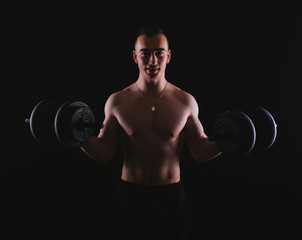 Fototapeta na wymiar Photo of happy fitness man working with dumbbells over dark background